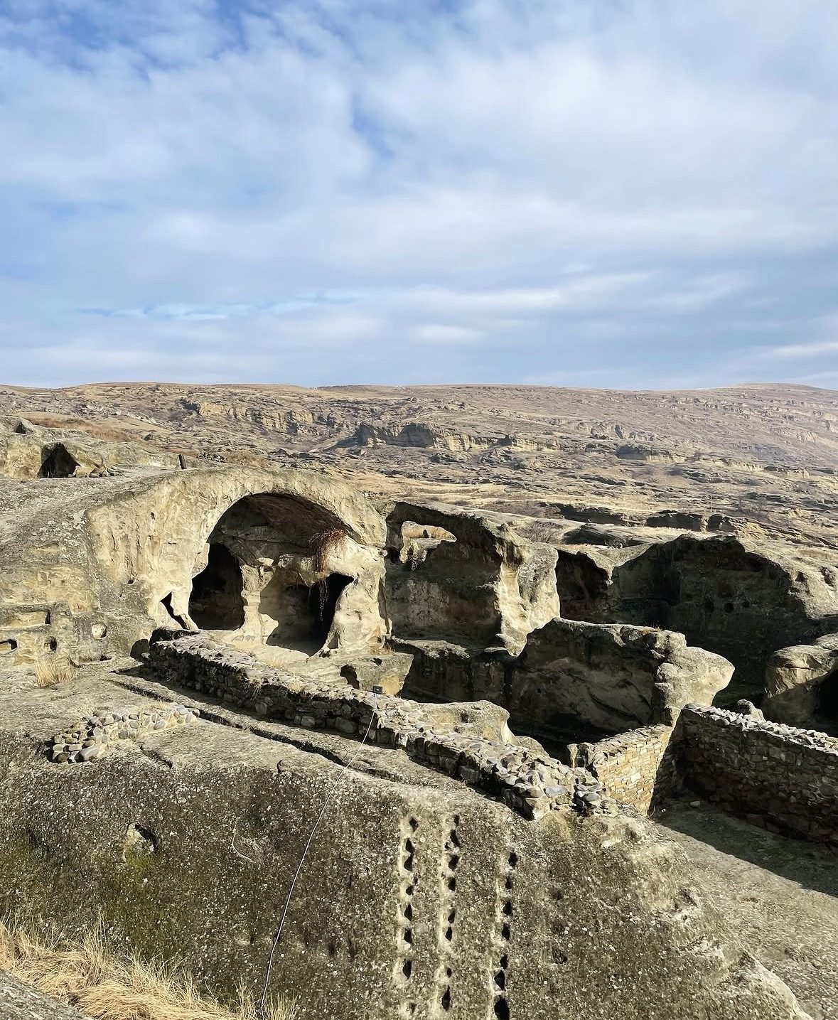 Panoramic view of Uplistsikhe cave city carved into rocky cliffs above the Mtkvari River, Georgia