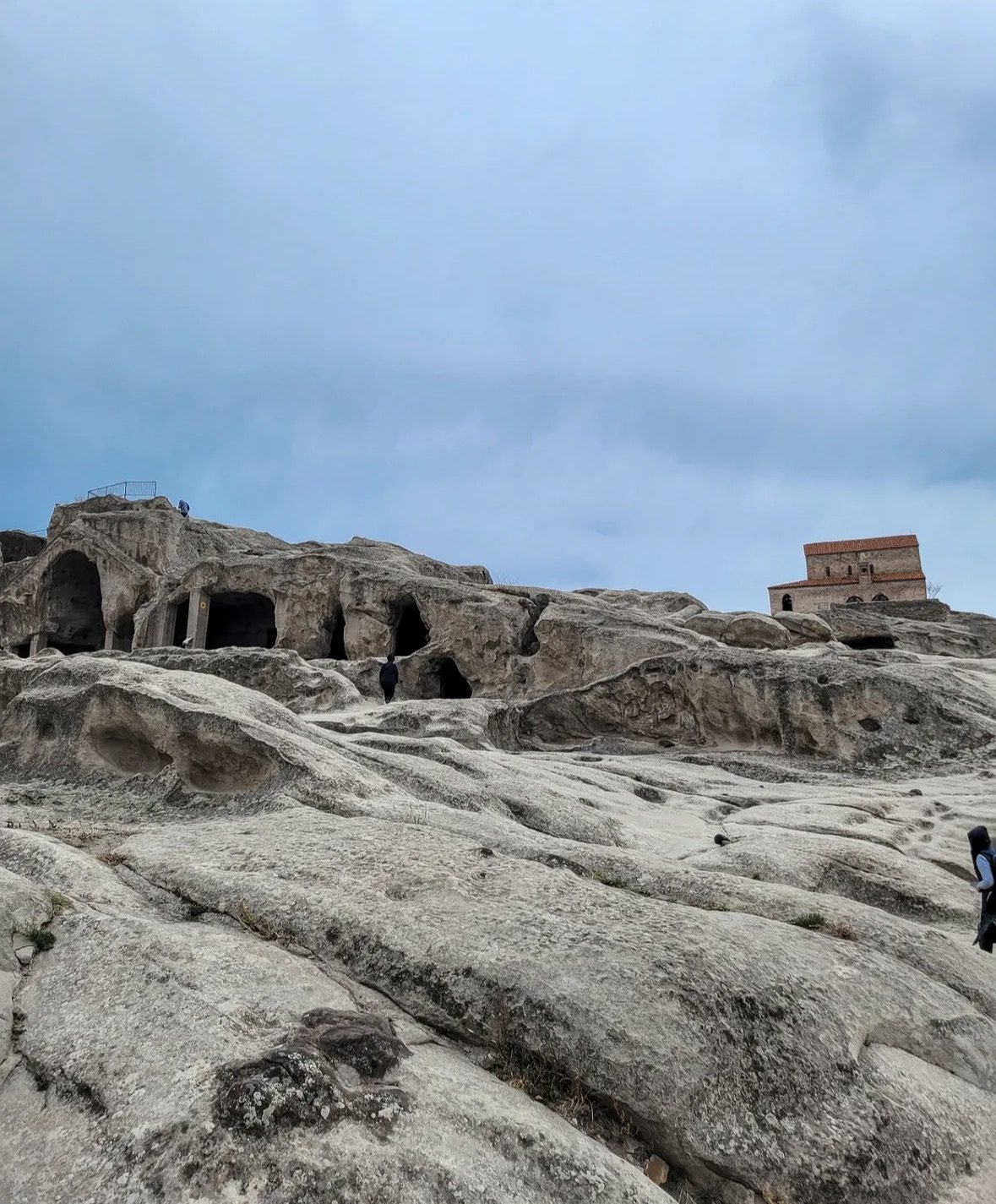 Local Georgian guide explaining rock carvings to tourists during an Uplistsikhe Tour